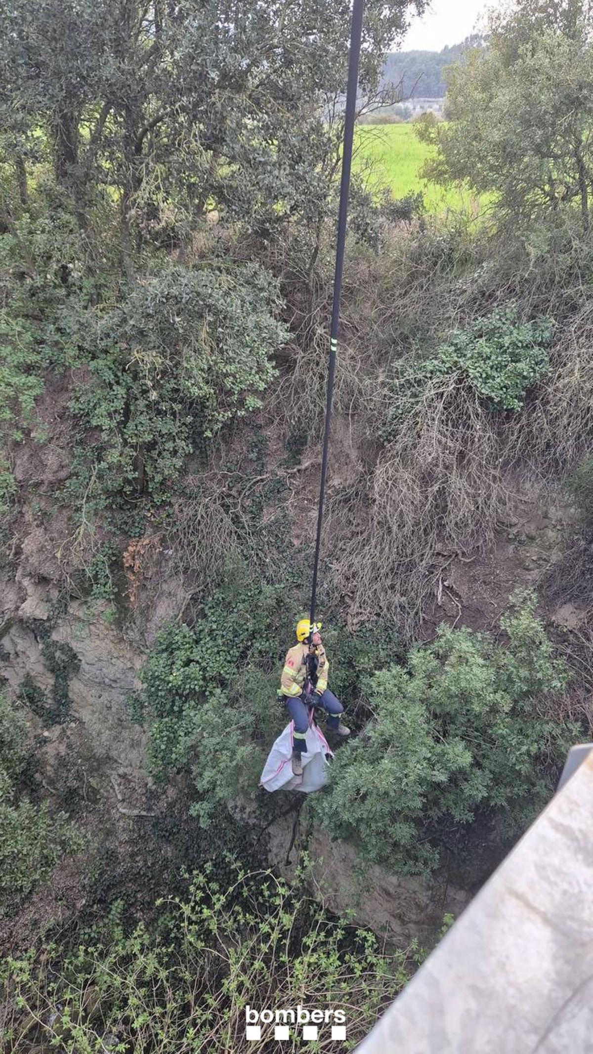 Imatge del Bomber pujant la gossa amb un gruatge fet des del camió escala