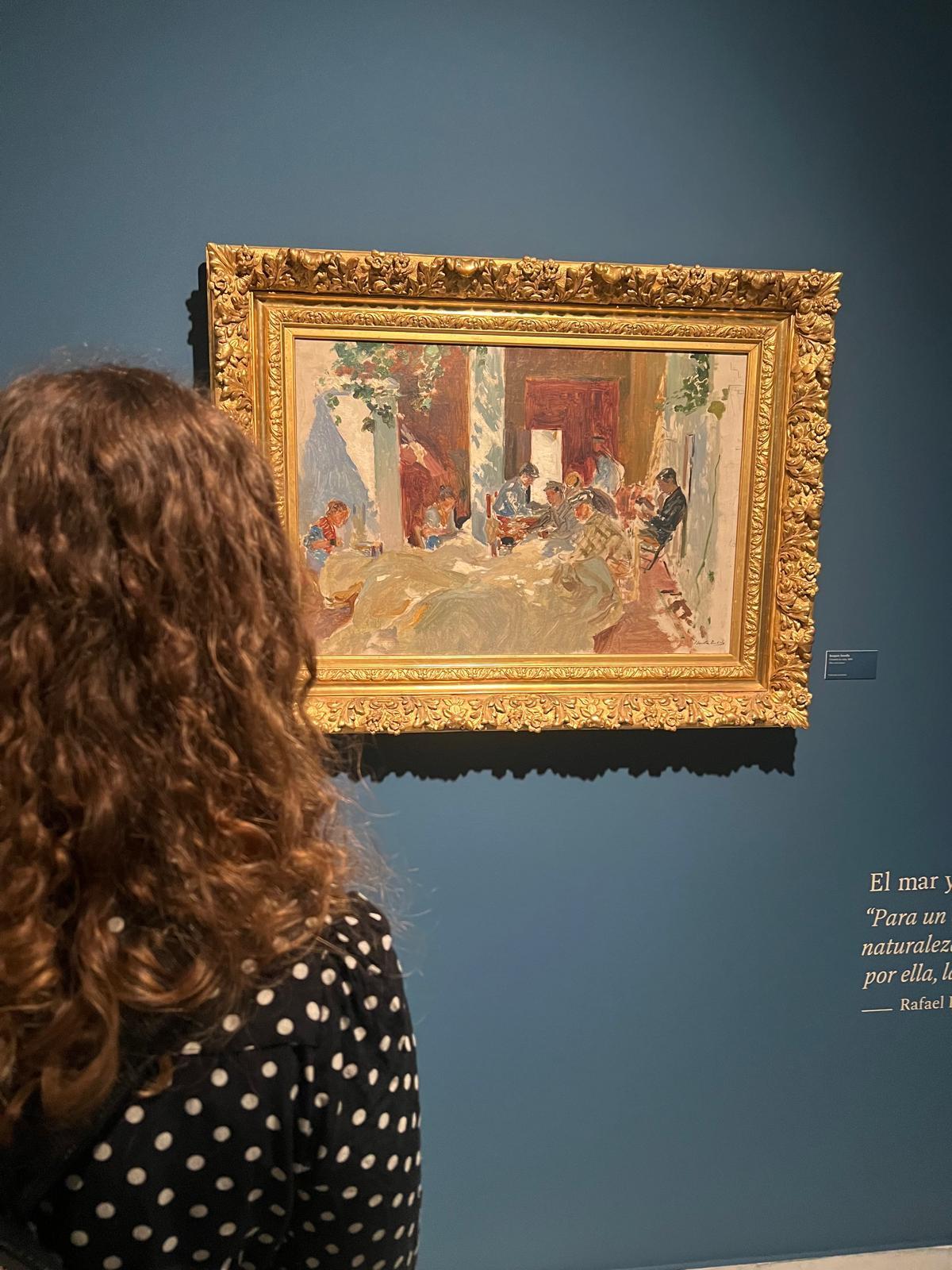 Una joven contempla el lienzo preparatorio 'Cosiendo las velas' de Sorolla, que se exhibe por primera vez.