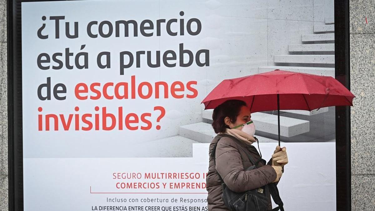 Una mujer camina junto a una sucursal bancaria.