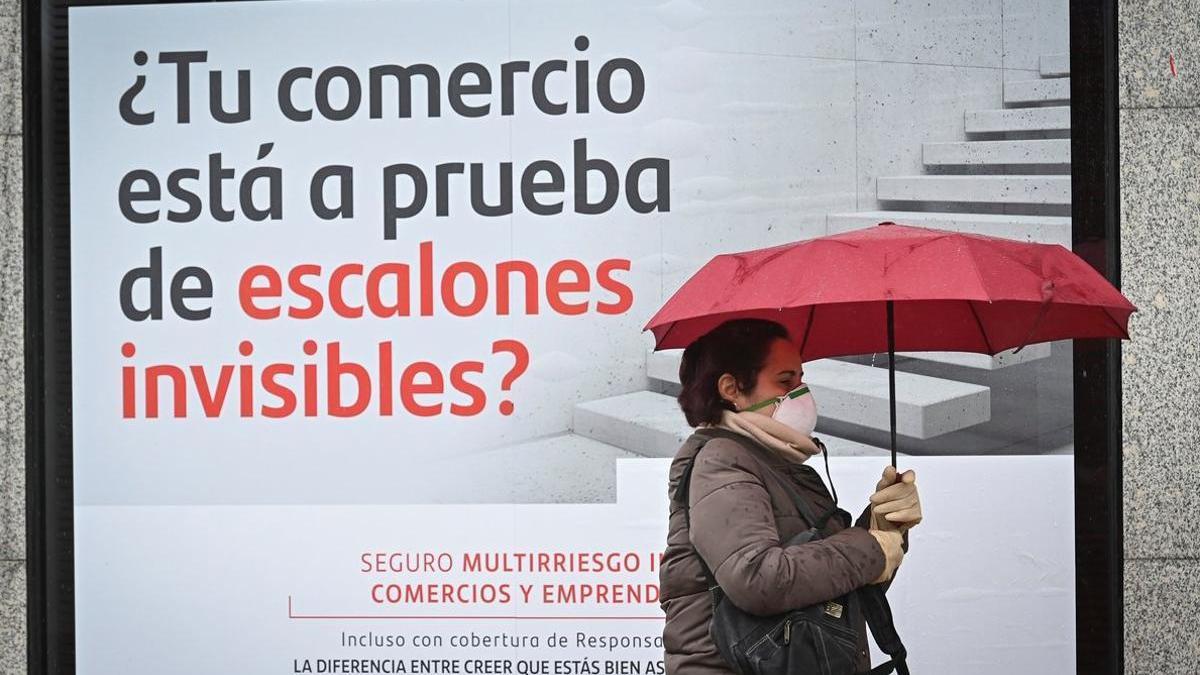 Una mujer camina junto a una sucursal del Banco Santander.