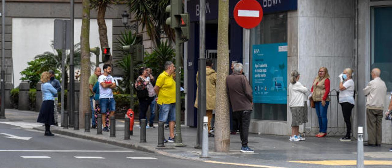 Un grupo de personas, alguna con mascarilla, aguarda en la entrada de una oficina bancaria de Las Palmas de Gran Canaria ayer, día de cobro de pensiones.