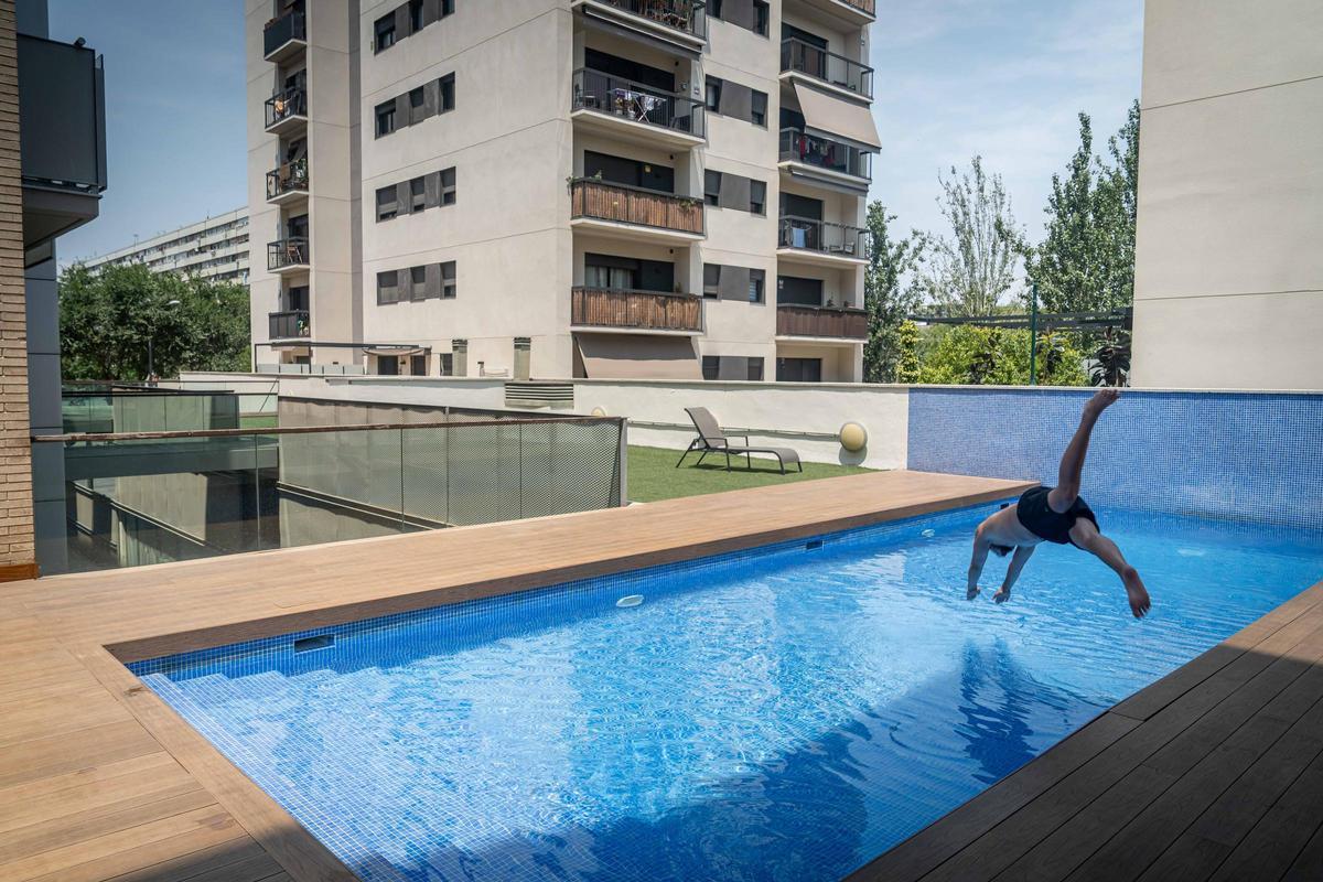 Un turista se lanza a la piscina de un bloque con apartamentos turísticos en el barrio de La Mina, en Sant Adrià de Besòs.
