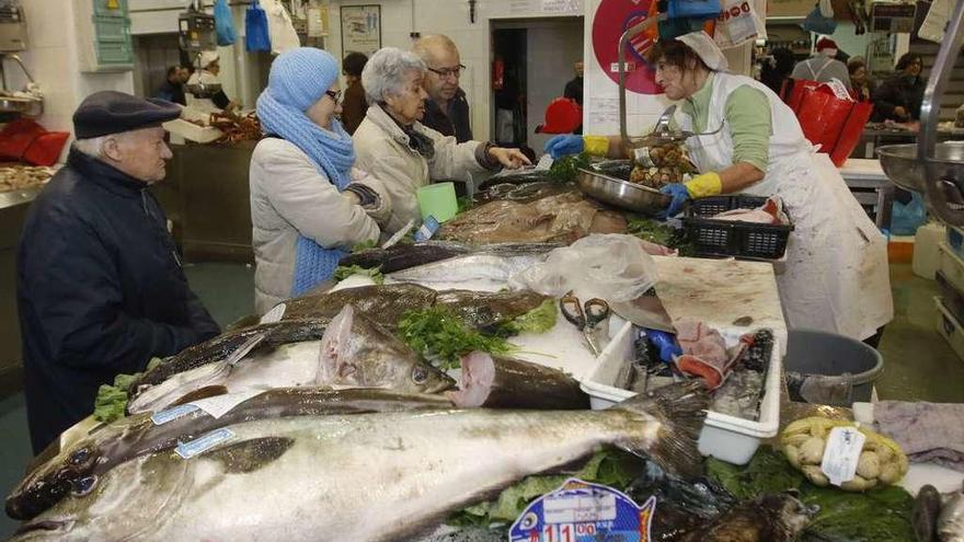 Clientes piden pescado de las rías gallegas para la última Navidad en una pescadería de Vigo. // Alba Villar