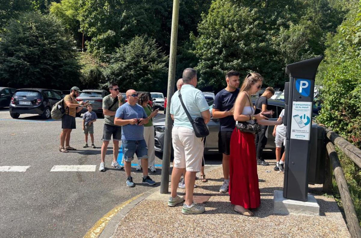 Varios visitantes hacen cola ante un parquímetro de Tazones.