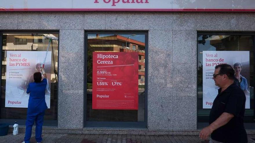 Un señor pasa por delante de una oficina del Banco Popular.