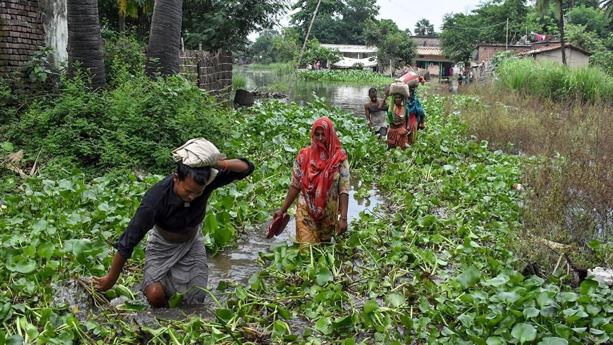 Los residentes de la aldea de Jaynagar en el distrito de Sitamarhi en el estado indio de Bihar llevan sus pertenencias entre las aguas de las inundaciones después de las fuertes lluvias monzónicas en julio de 2019