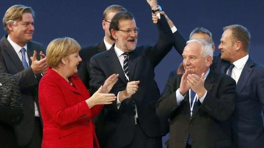 El presidente del Consejo Europeo, Donald Tusk (d.) levanta el brazo de Mariano Rajoy, junto al líder del PPE, Joseph Daul (2d.), y Ángela Merkel. // Efe