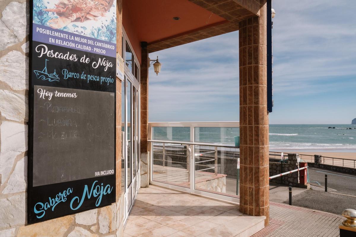 La pizarra borrada de uno de los restaurantes cerrados que da a la playa de Tregadín de Noja.