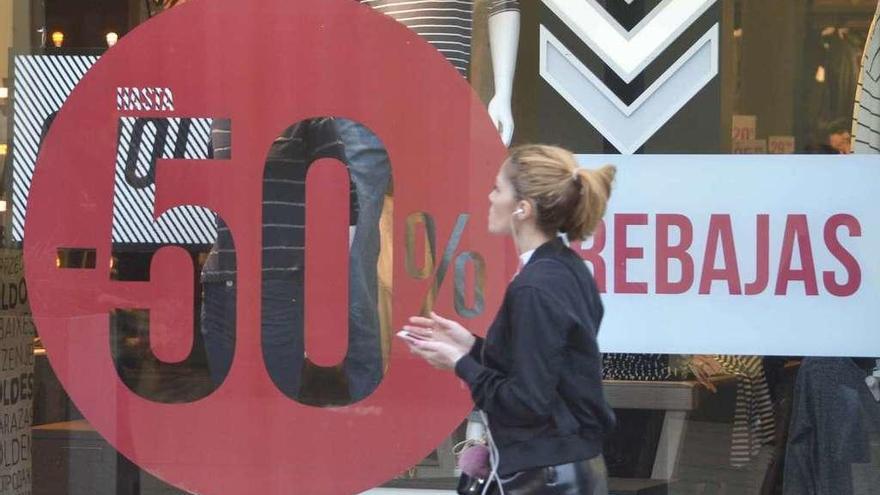 Una chica pasa por delante de una tienda que anuncia las rebajas.