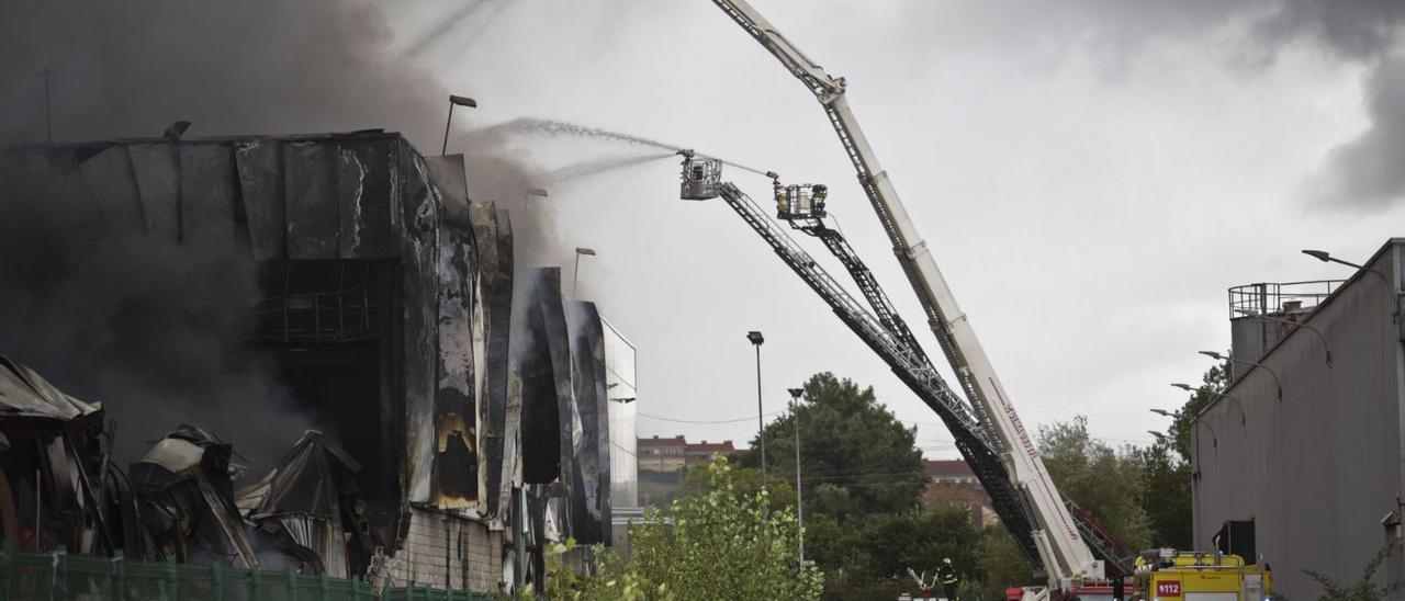 Efectivos de bomberos del Principado y del Ayuntamiento de Oviedo, sofocando las llamas en dos naves del polígono de Silvota, en agosto de 2020. | I. Collín