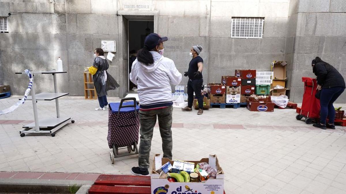 Personas esperan grandes colas para recoger alimentos gratis.