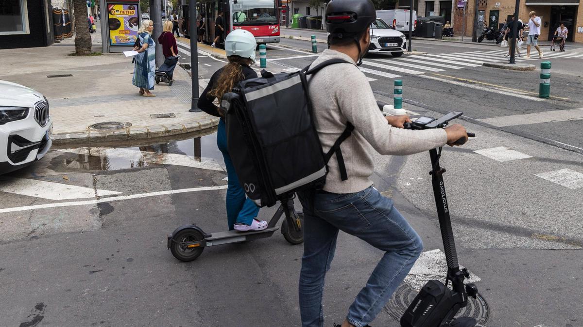 Dos usuarios de patinetes esperan a que pase el bus para incorporarse a la vía.
