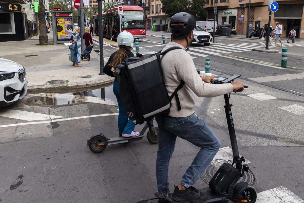 Dos usuarios de patinetes esperan a que pase el bus para incorporarse a la vía.