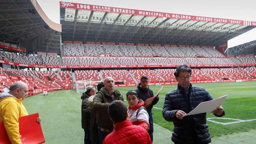 Aficionados sportinguistas colocan las cartulinas para el mosaico en los asientos de El Molinón.