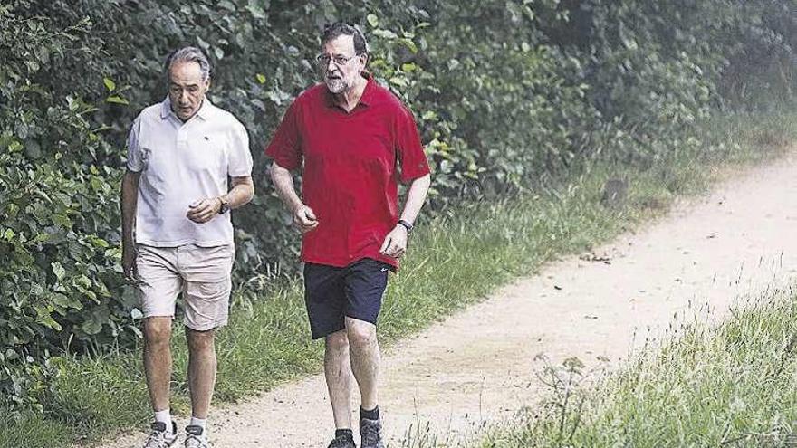 Rajoy, de rojo, durante la caminata en Ribadumia; a su lado José Benito Suárez, marido de la presidenta del Congreso Ana Pastor. // Efe