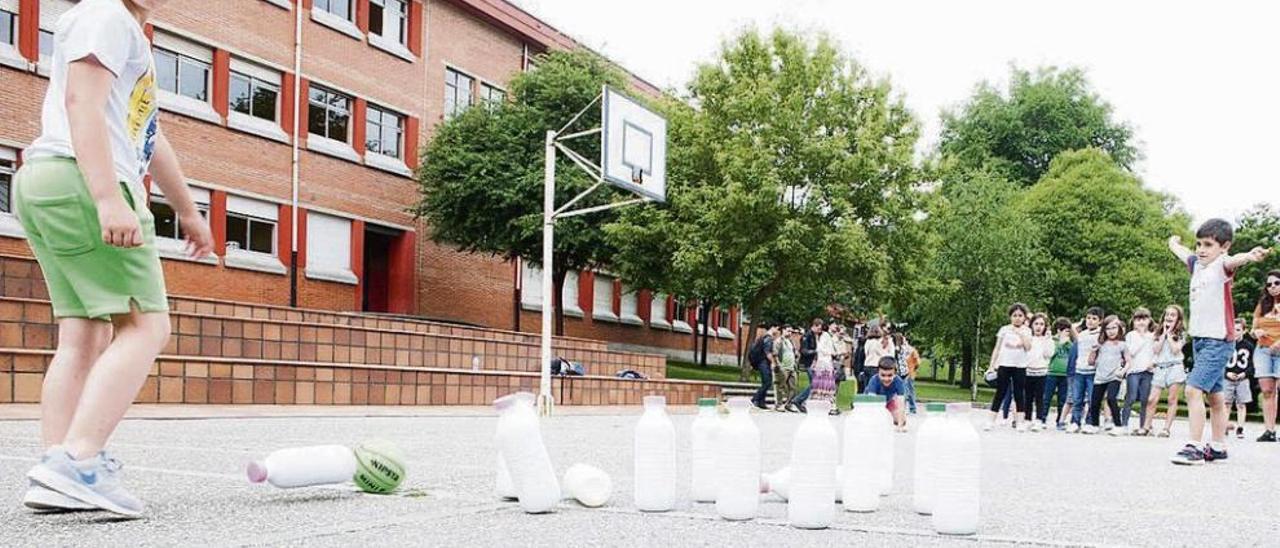 Un grupo de niños juega a los bolos con botellas de leche recicladas.