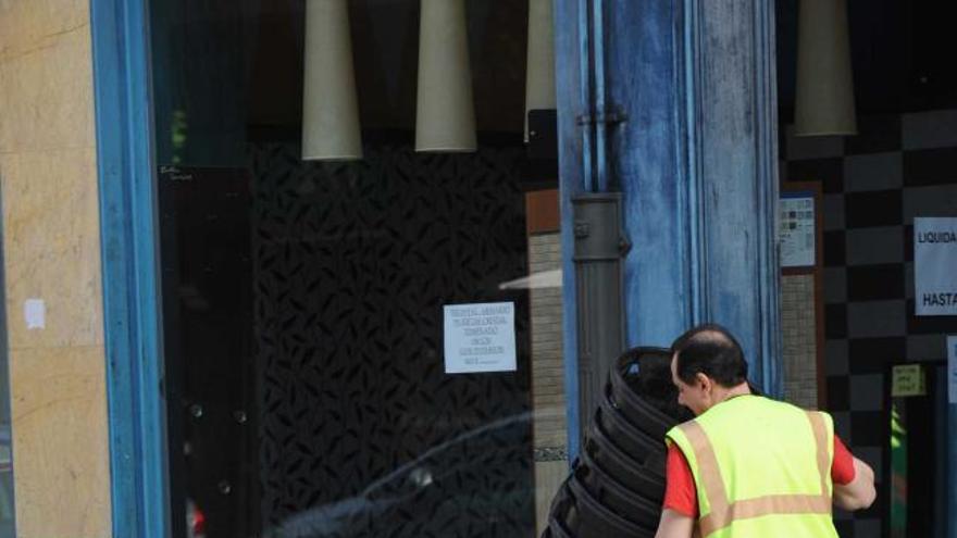 Un operario coloca cubos de recogida de basura en Mieres.