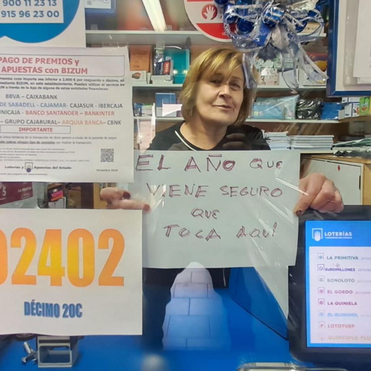 Montserrat Álvarez, con un cartel  «optimista», en el mostrador de su  estanco de Campomanes (Lena).