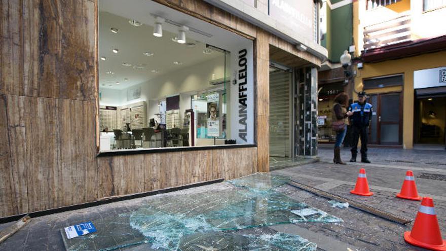 Luna rota de la óptica Alain Afflelou, en la calle San Bernardo, tras sufrir el impacto de una tapa de alcantarilla.