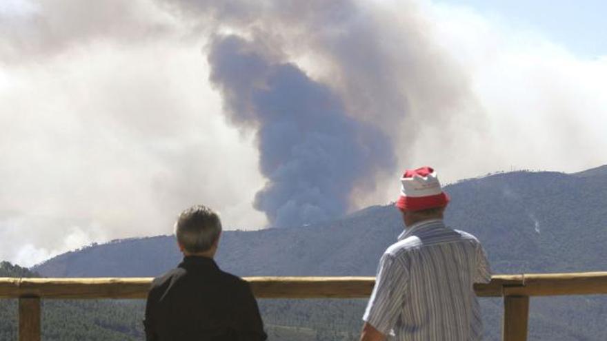 Vecinos de El Robledo (Cáceres) observan el humo que sale del incendio forestal que permanece activo desde el pasado sábado en la comarca cacereña de Las Hurdes.