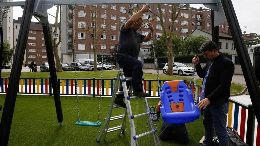 Dos operarios instalan el columpio adaptado en el parque infantil de Vetusta.