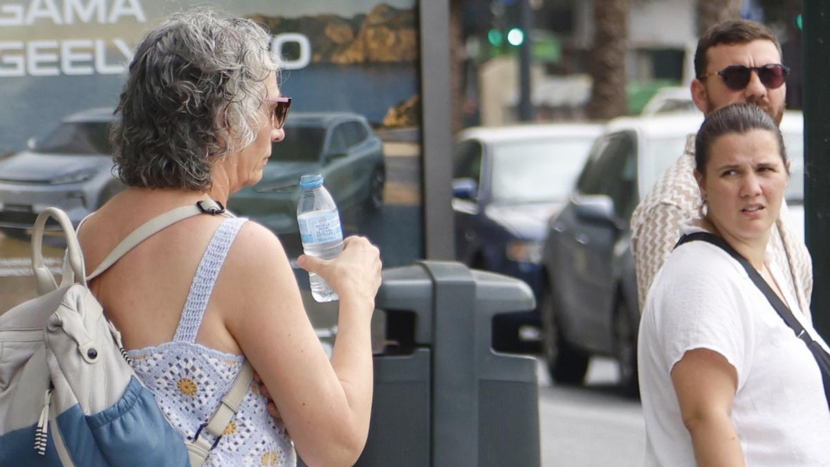 Una mujer bebe agua para contrarrestar el calor.