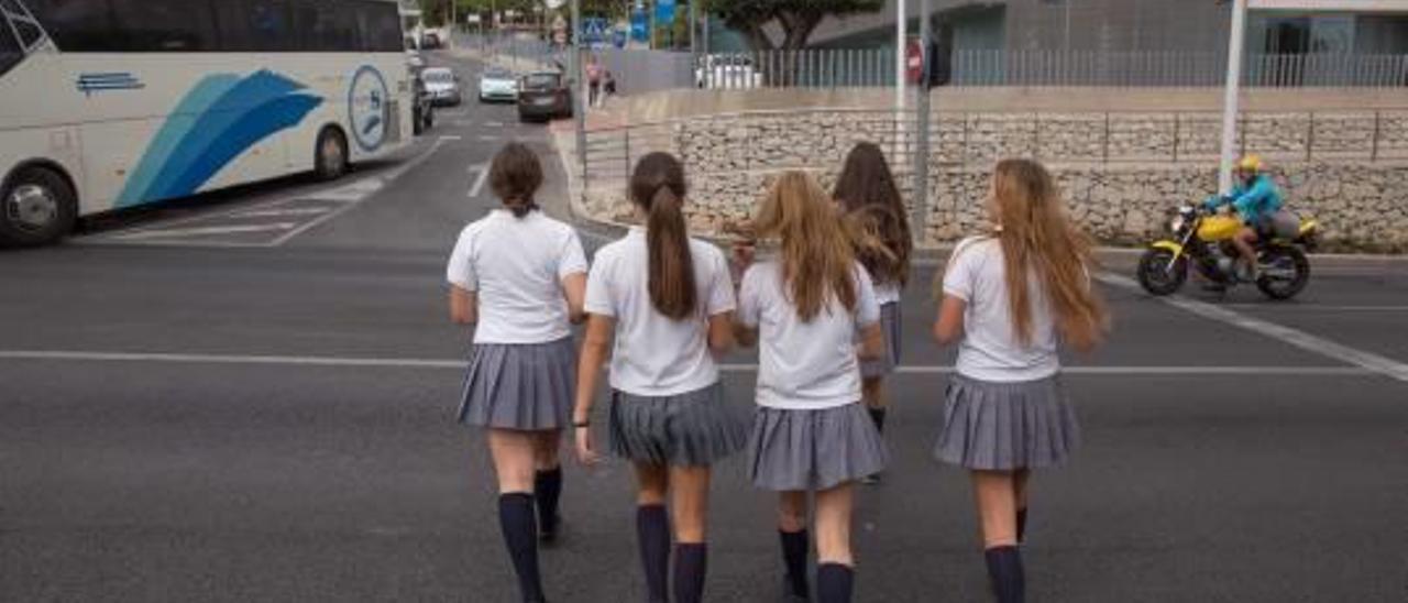 Un grupo de estudiantes de Jesuitas cruza indebidamente la avenida de Dénia en un momento en el que el tráfico está parado por un semáforo pese a tener un paso frente a su colegio