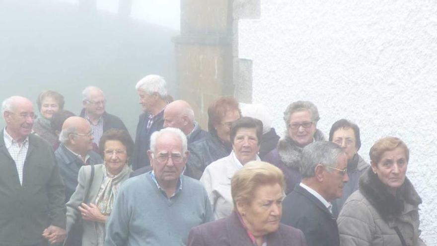 Los visitantes, en un lateral de la ermita del Acebo, envuelta en niebla.