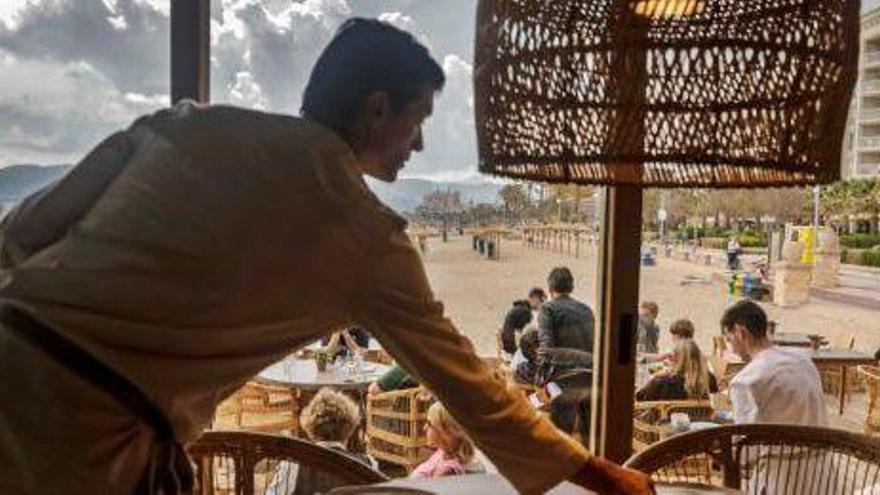 Un camarero monta una mesa en un restaurante de la bahía de Palma.