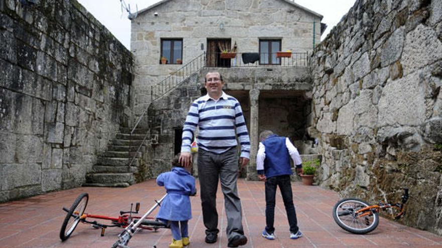 José Antonio Viqueira, en la entrada de su casa de Cuñas, con dos de sus cuatro hijos.  // Noé Parga