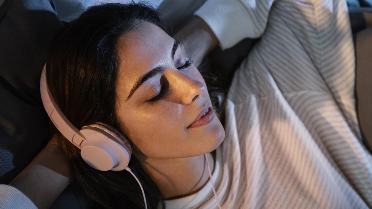 Una mujer con auriculares en la cama