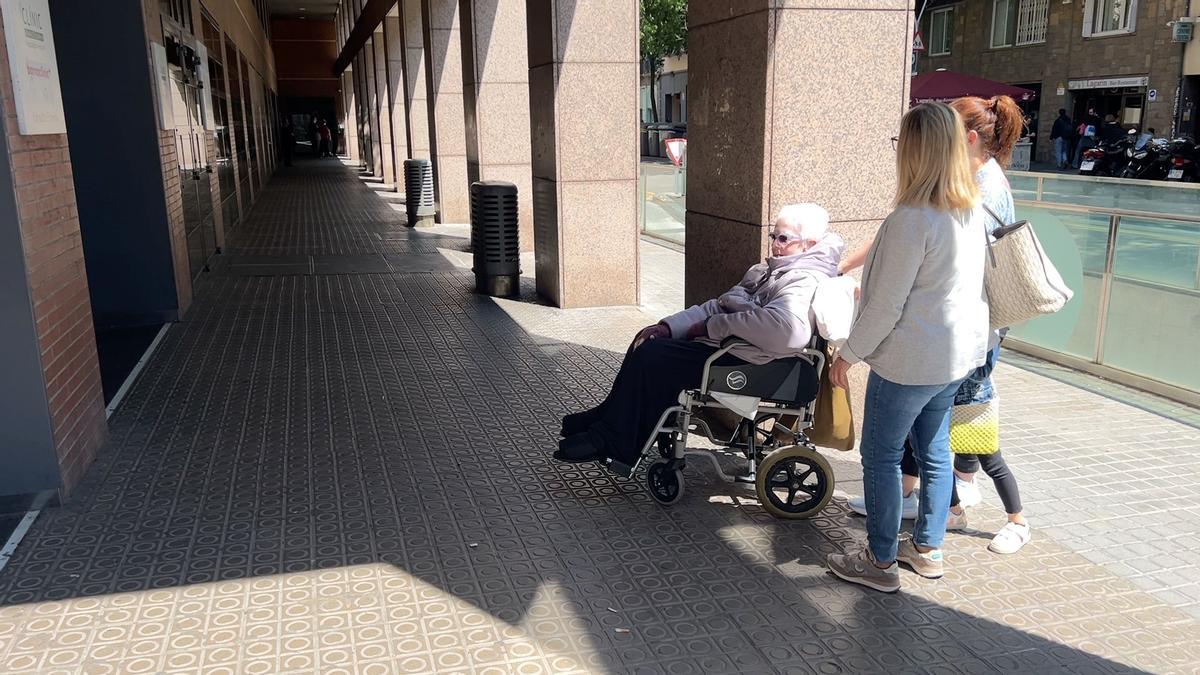 Alba aguarda con una familiar en silla de ruedas frente a las consultas externas del Clínic poder subir a casa cuando el ascensor esté operativo.