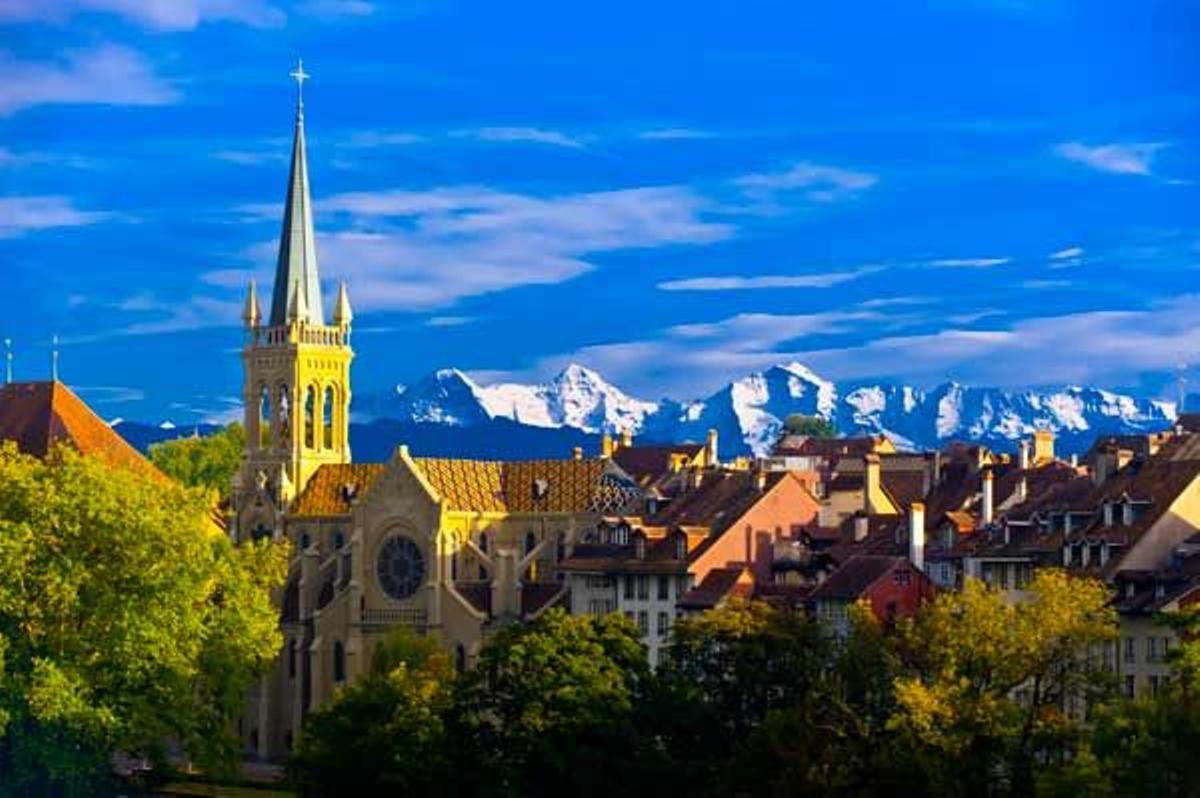 Iglesia de los San Pedro y San Pablo en el centro medieval de Berna, con los picos de los Alpes Suizos detrás.