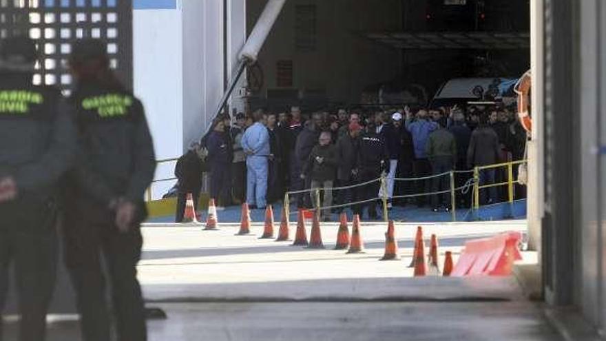 Numerosos pasajeros, vigilados por la Guardia Civil, esperan a bordo del &#039;ferry&#039; (derecha) para poder bajar a tierra. / efe