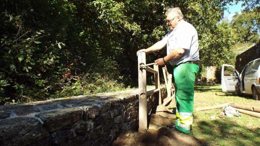 Un operario coloca el vallado de madera junto al muro exterior del monasterio.