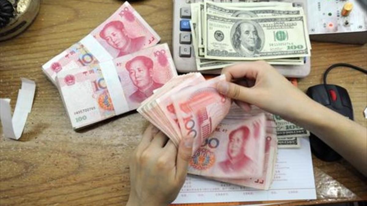 La trabajadora de un banco cuenta billetes de 100 yuanes en la ciudad china de Hifei, en China.