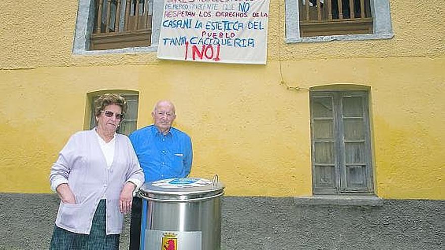 Paz Isidro y Ovidio Méndez, junto a uno de los contenedores instalados al lado de su casa y bajo una pancarta.