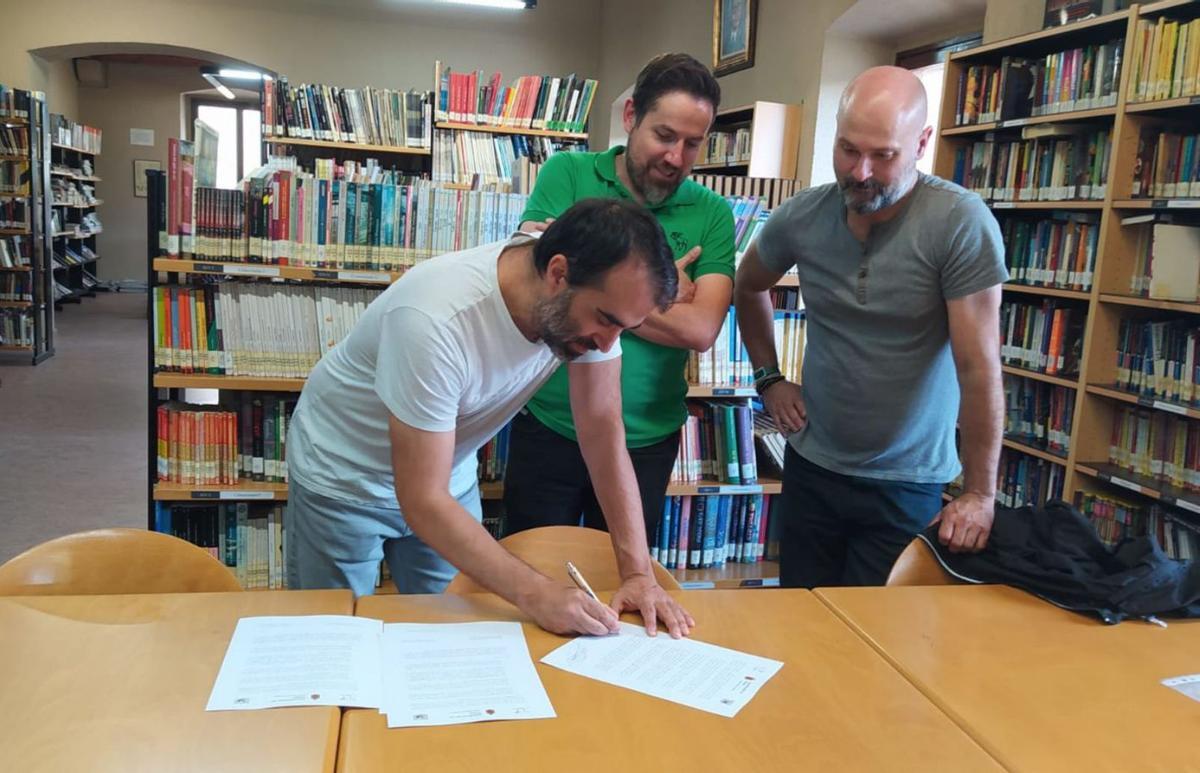 Antón Lombardero firma el acuerdo en presencia de Diego Nieto y Daniel Menéndez, en la biblioteca. | I. C. R.