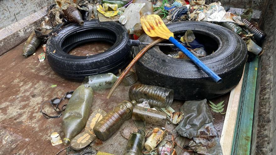 Arriba, parte de la basura recogida por el grupo de submarinistas de la Asociación Sanabria Desarrollo Sostenible, que posan a la izquiera de estas líneas. | Cedidas