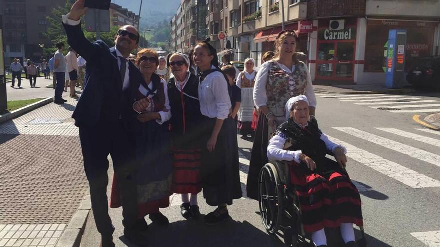 La nonagenaria Lola Mayor (a la derecha en silla de ruedas) participa en el desfile del concurso de sidra casera de Piloña junto al pregonero.