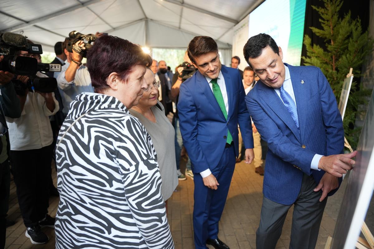 El presidente de la Junta de Andalucía, Juanma Moreno (d), muestra unos paneles explicativos del metro a unas vecinas del barrio de Pino Montano. A 25 de septiembre de 2024, en Sevilla (Andalucía, España). Acto de inicio de obras del tramo 2 (Los Mares-San Lázaro) de la línea 3 Norte del Metro de SevillaMoreno preside este miércoles el inicio de obras del segundo subtramo del tramo norte de la línea 3 del metro de Sevilla. Este miércoles comienzan las obras del segundo subtramo del tramo norte de la línea tres del metro de Sevilla, actualmente en marcha con la construcción del ramal técnico y del primer subtramo subterráneo en Pino Montano; después de que esta nueva fase del proyecto fuese adjudicada el pasado mes de mayo a una unión temporal de empresas (UTE) conformada por Azvi, Dragados y Martín Casillas, por más de 105,6 millones de euros. 25 SEPTIEMBRE 2024 María José López / Europa Press 25/09/2024 / JUANMA MORENO;María José López;