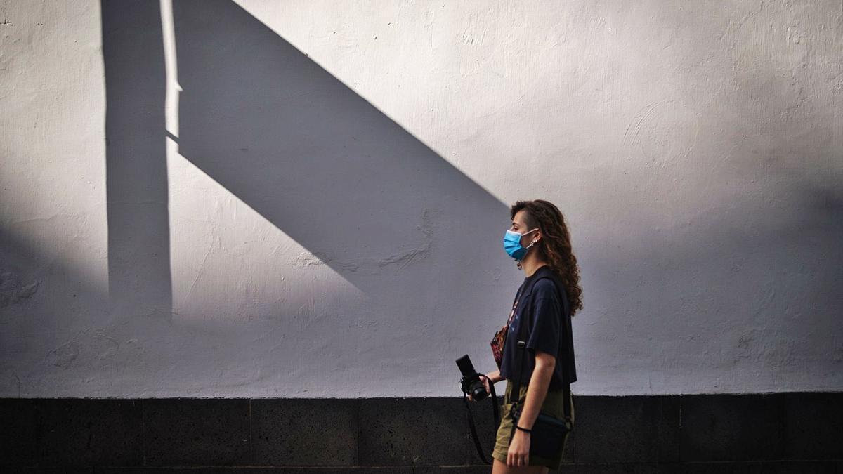 Una joven camina por Santa Cruz de Tenerife con mascarilla.