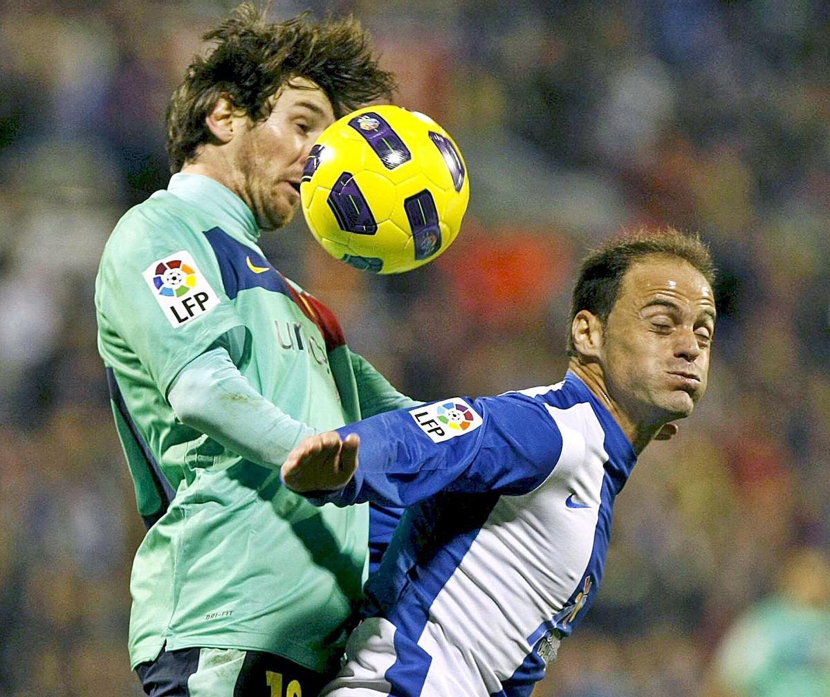 Messi, cabizbajo, con los futbolistas del Hércules de fondo celebrando un tanto el día de la victoria del conjunto blanquiazul en la temporada 2010/11. | E. FONTCUBERTA / M. LORENZO/ EFE