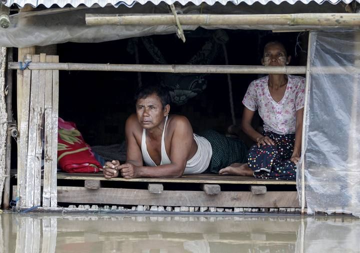 People sit at their home in a flooded village outside Zalun Township, Irrawaddy Delta