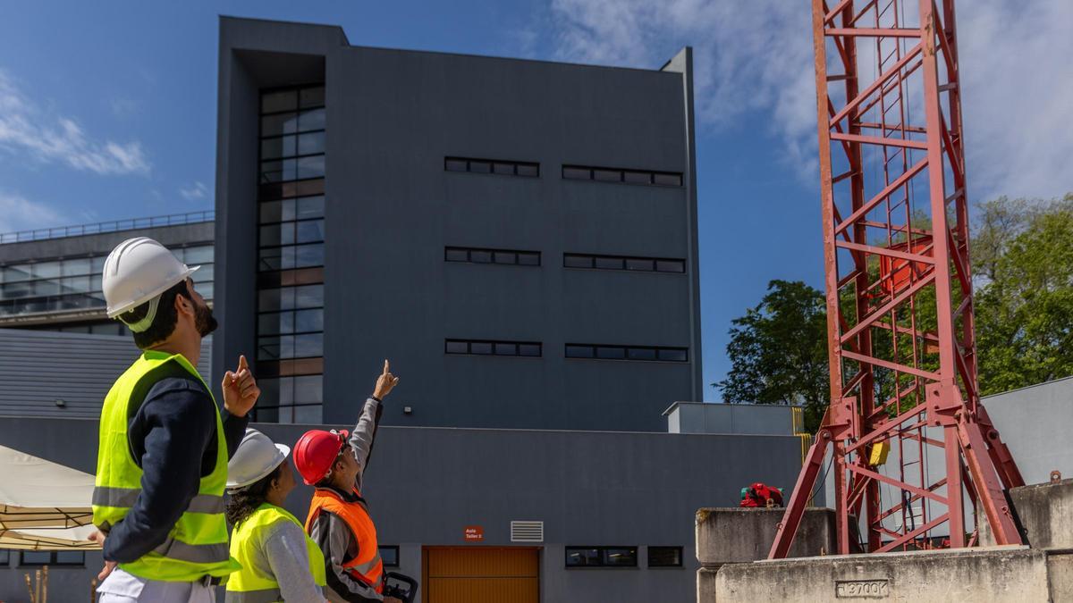 Juan Ángel (derecha) enseña a dos alumnos a manejar una grúa de construcción.