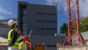 Juan Ángel (derecha) enseña a dos alumnos a manejar una grúa de construcción.
