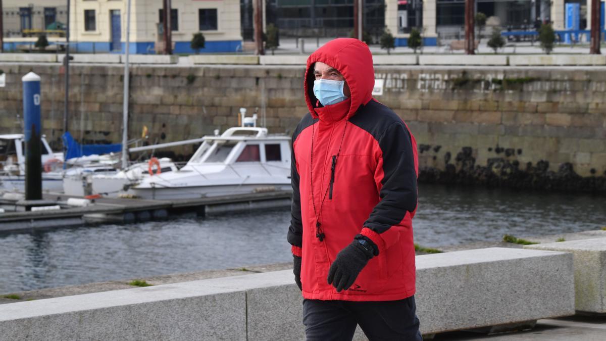 Un hombre camina, abrigado, junto al puerto de A Coruña.