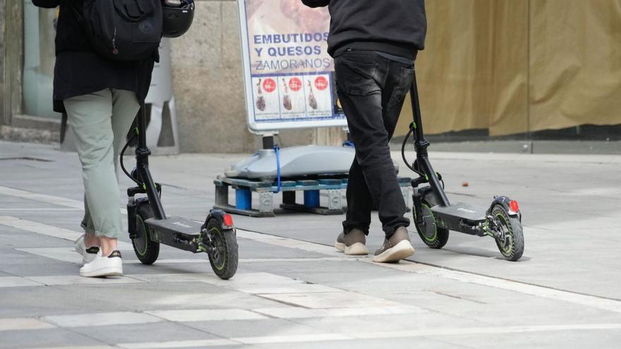 Jóvenes con patinetes por las calles peatonales.