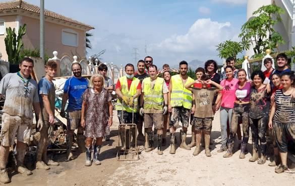 Voluntarios, llenos de barro, en una urbanización.