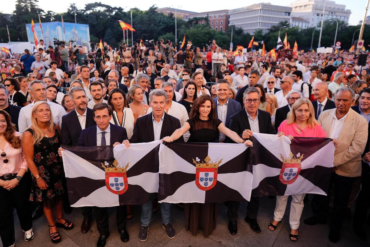 Feijóo, Ayuso y Almeida sosteniendo una bandera de Ceuta durante la manifestación.